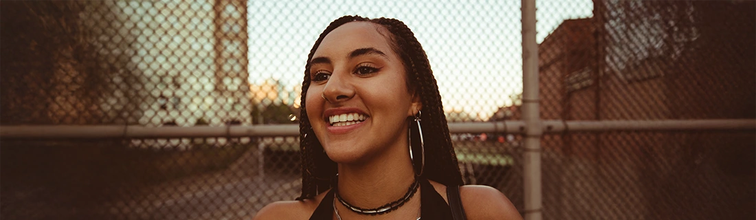 Woman Smiling In Front Of Metal Fence